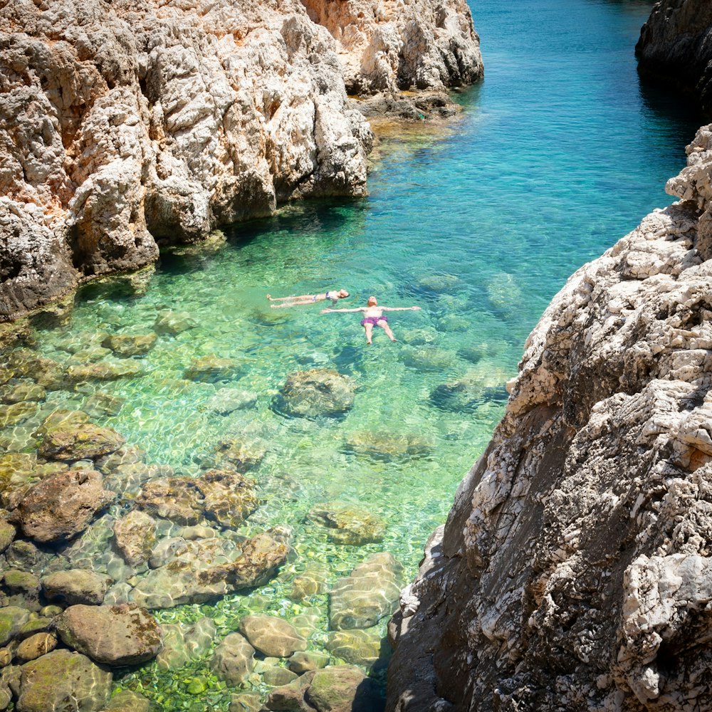 a person in a body of water surrounded by rocks