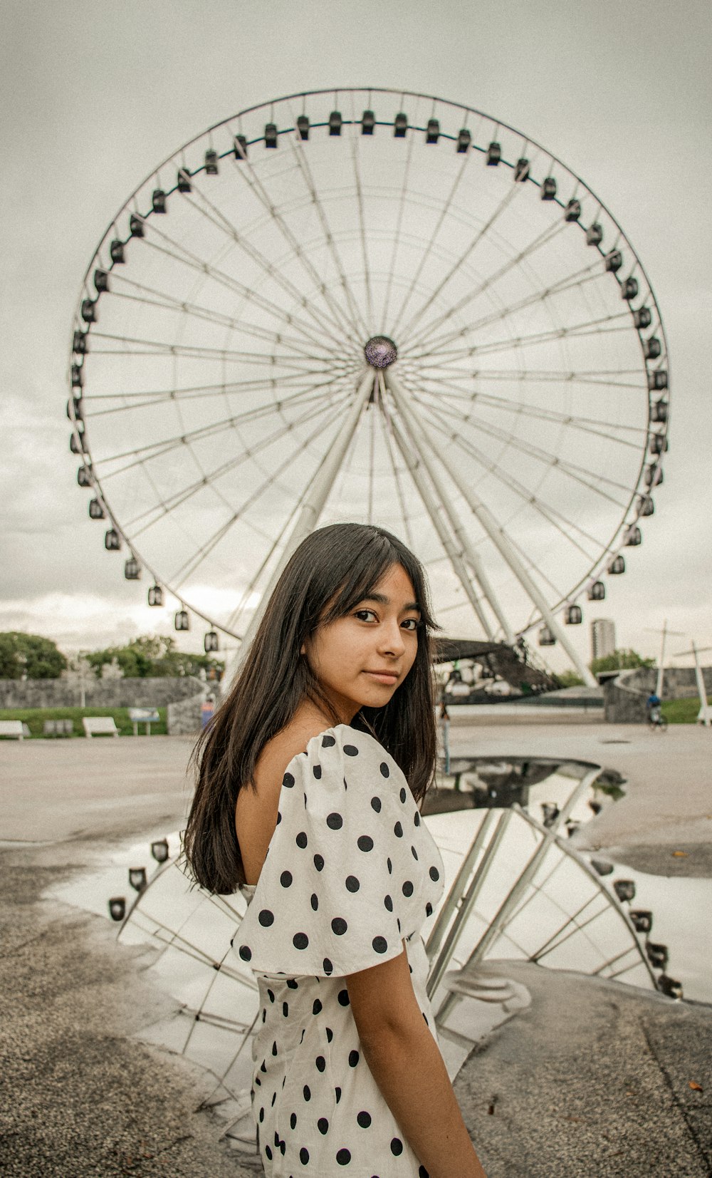 a woman standing in front of a ferris wheel