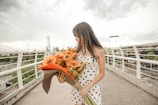 a woman holding a bouquet of flowers on a bridge