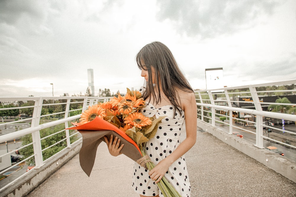 a woman holding a bouquet of flowers on a bridge