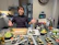 Man happily packaging sushi sweets in a neat home office setup with laptop and notes