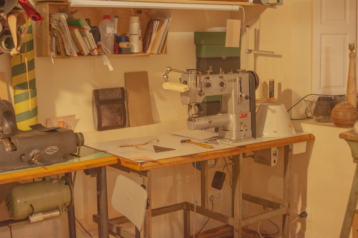The far bench at the end of the day, the machine threaded and a half-cut length of cloth still pinned flat