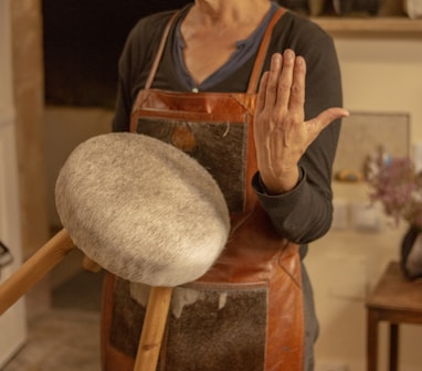 a woman in a brown apron holding a wooden spatula