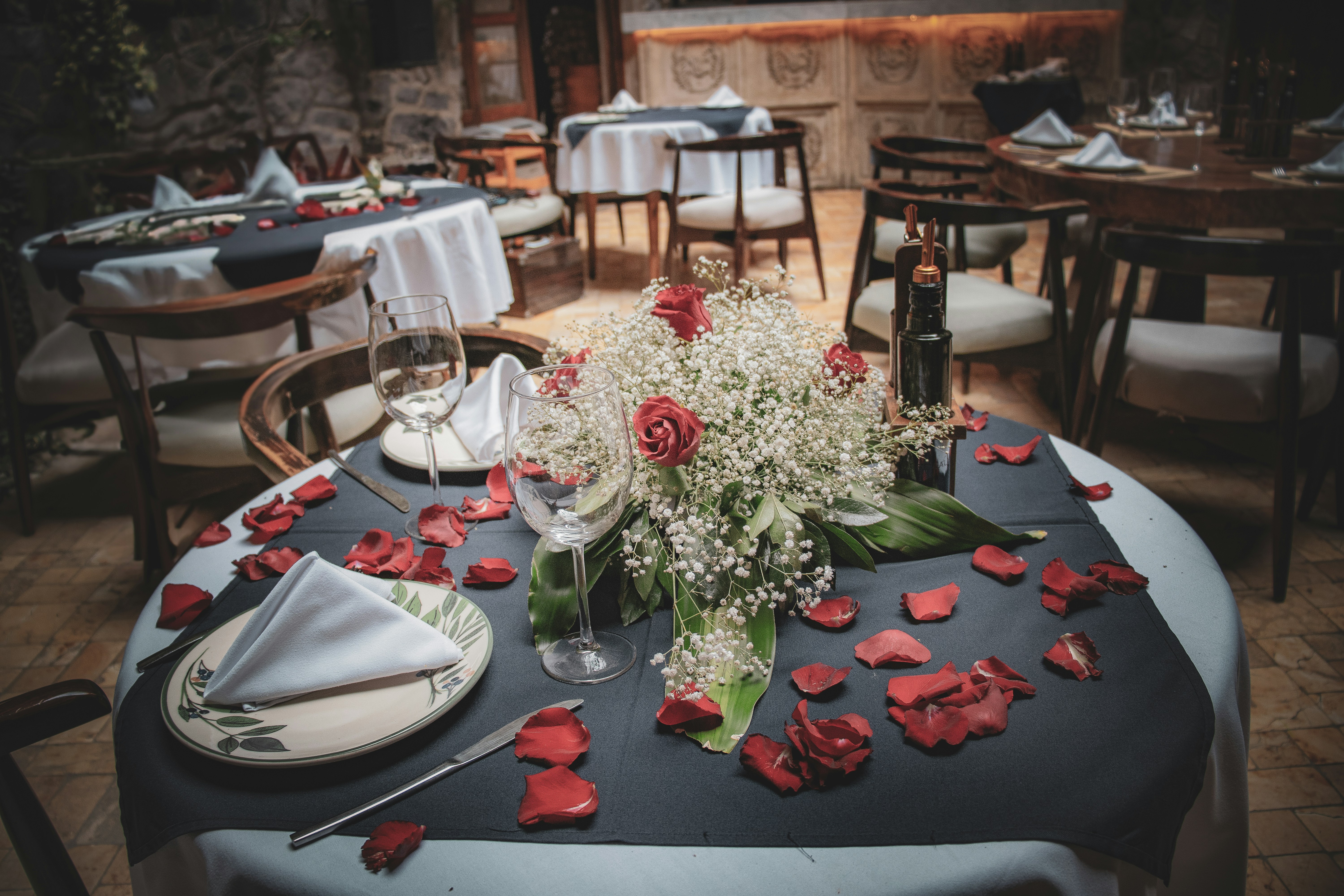 Romantic rose petals scattered around champagne and gift box, candlelit warm ambiance