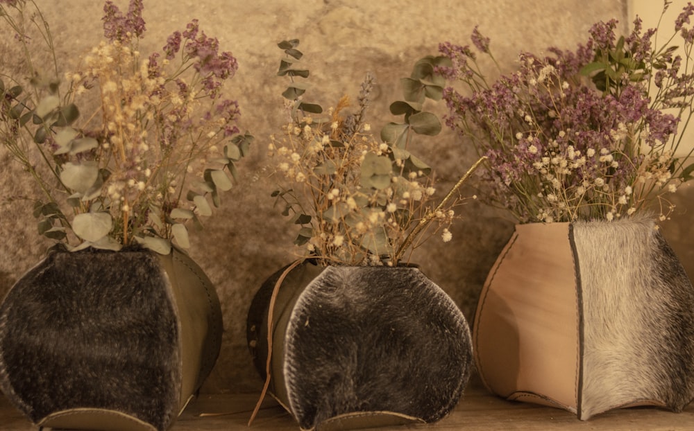 three vases with flowers in them sitting on a shelf