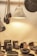 A collection of handcrafted items sits on display. The setup includes a variety of objects such as bowls, trays, and a hanging lamp, all of which have a fur or leather-like texture. The scene is warmly lit, enhancing the natural materials of each item. Wooden utensils with a dark finish are suspended next to the lamp.