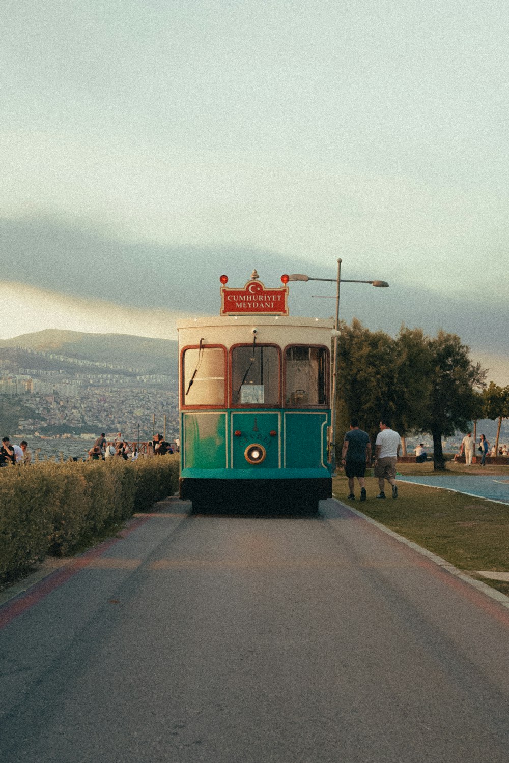 a green and white trolley car traveling down a street