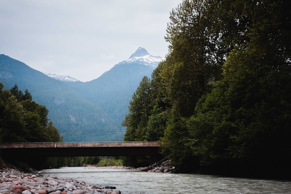 a bridge over a river with mountains in the background