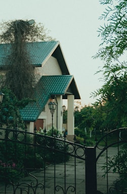 a white house with a green roof and a black fence