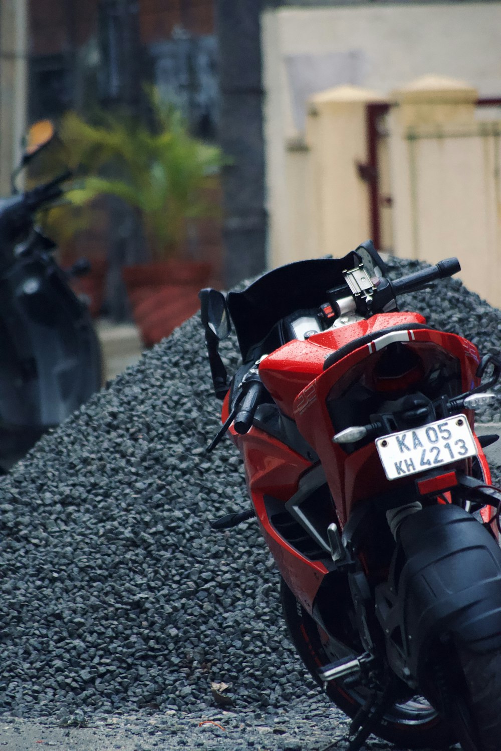 a red motorcycle parked next to a pile of gravel