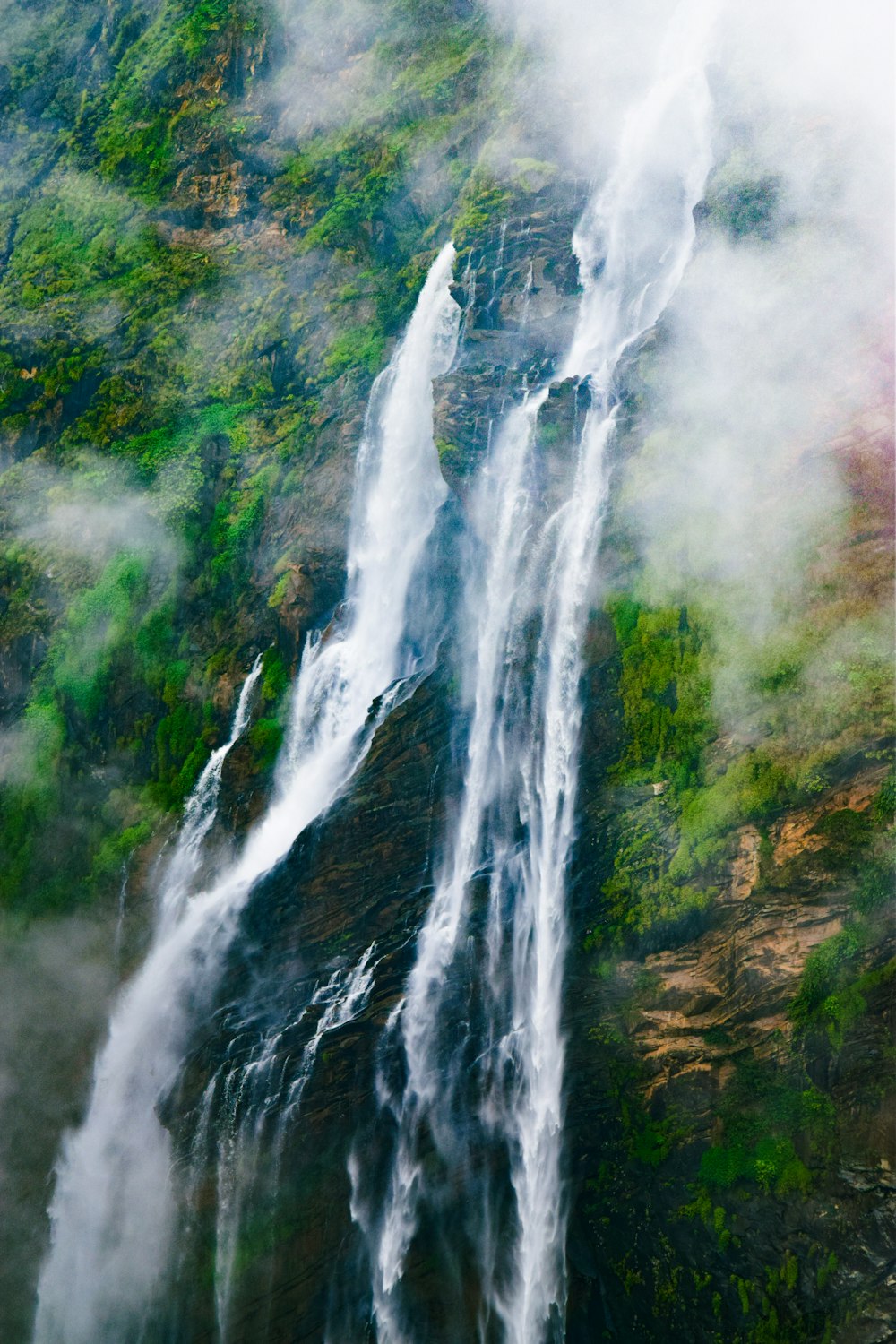 a very tall waterfall in the middle of a forest