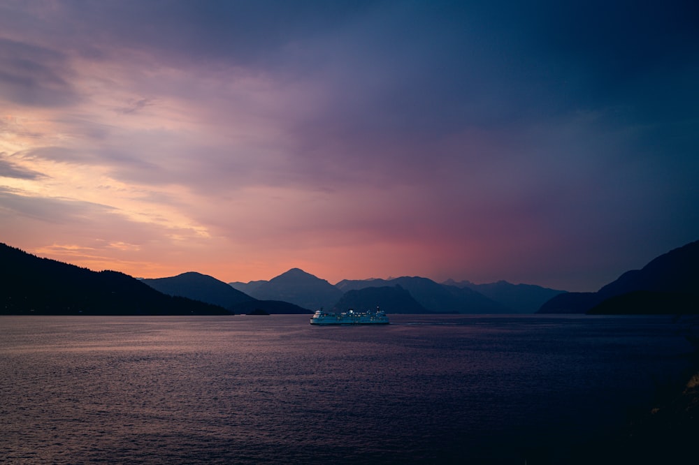 a boat in a body of water with mountains in the background