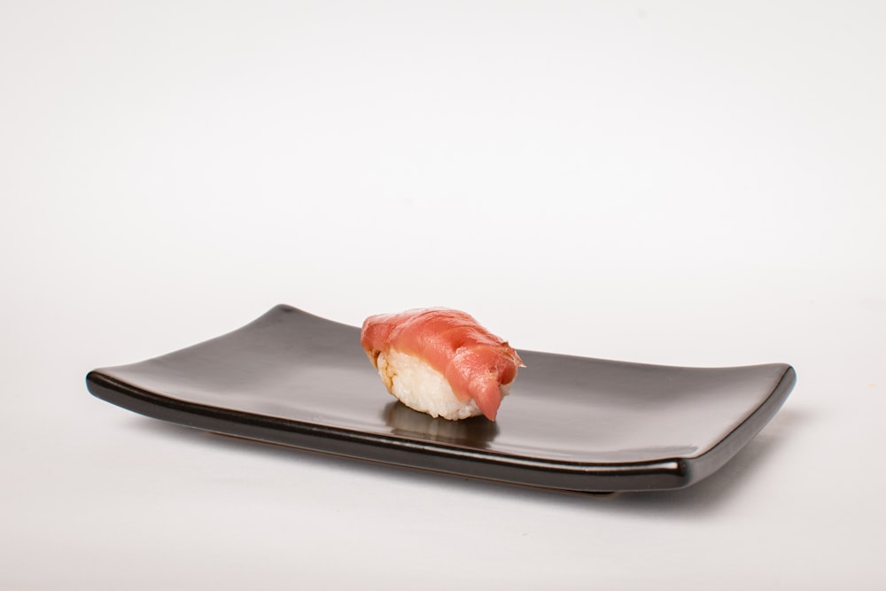 a piece of sushi on a black plate