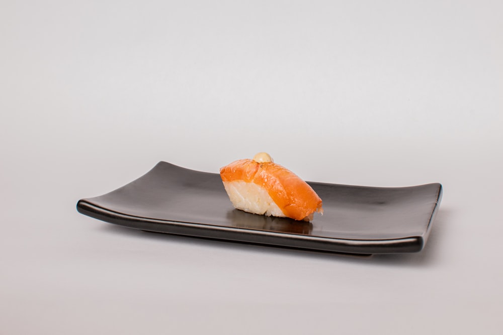 a piece of sushi on a black plate