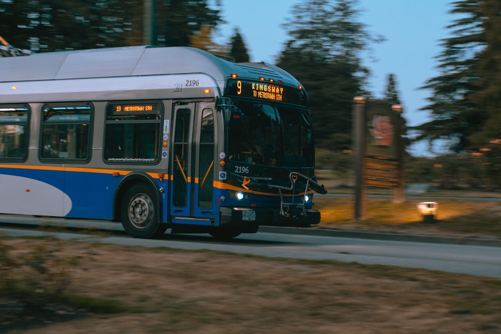 a blue and white bus driving down a street