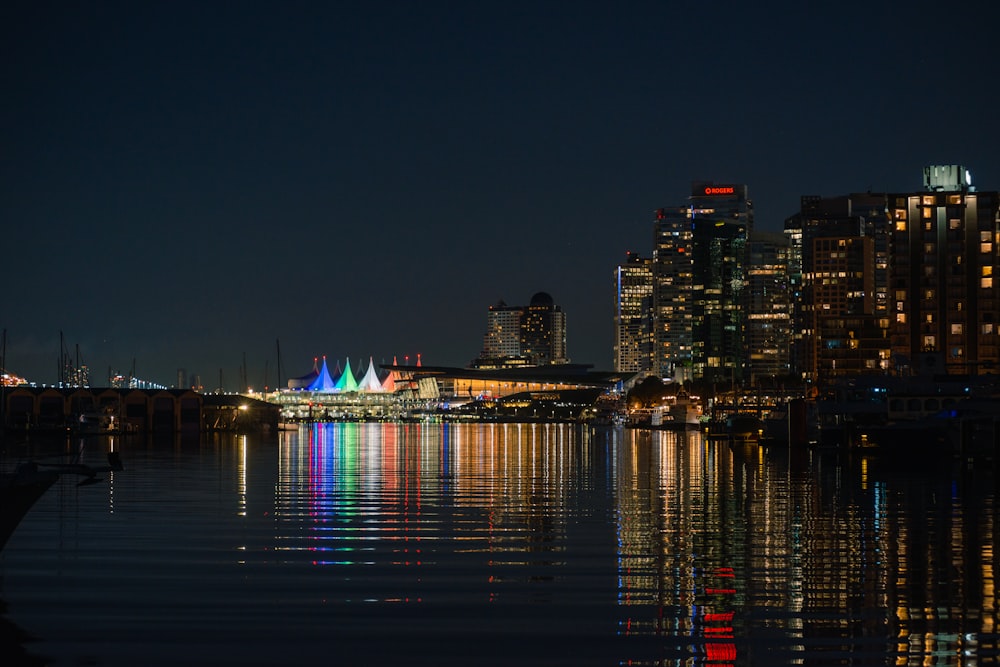 a city skyline is reflected in the water at night