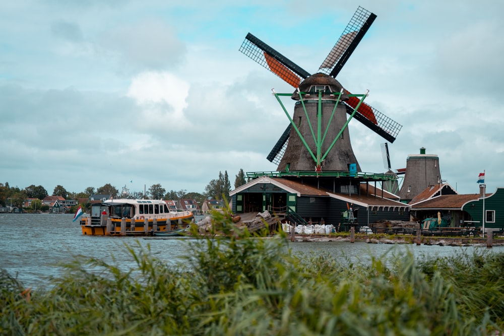 a boat traveling down a river next to a windmill
