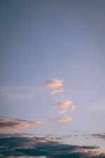 A serene anime-inspired scene showing a glowing sky with gentle gradients and floating cloud elements.