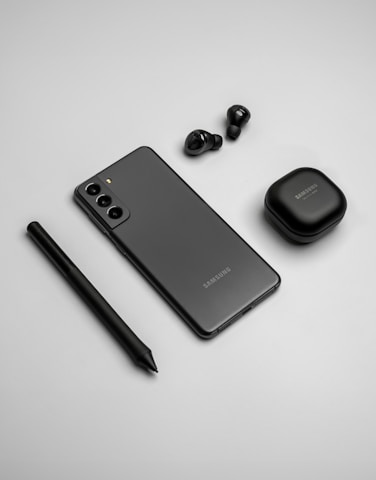 a cell phone, ear buds, and a pen on a table