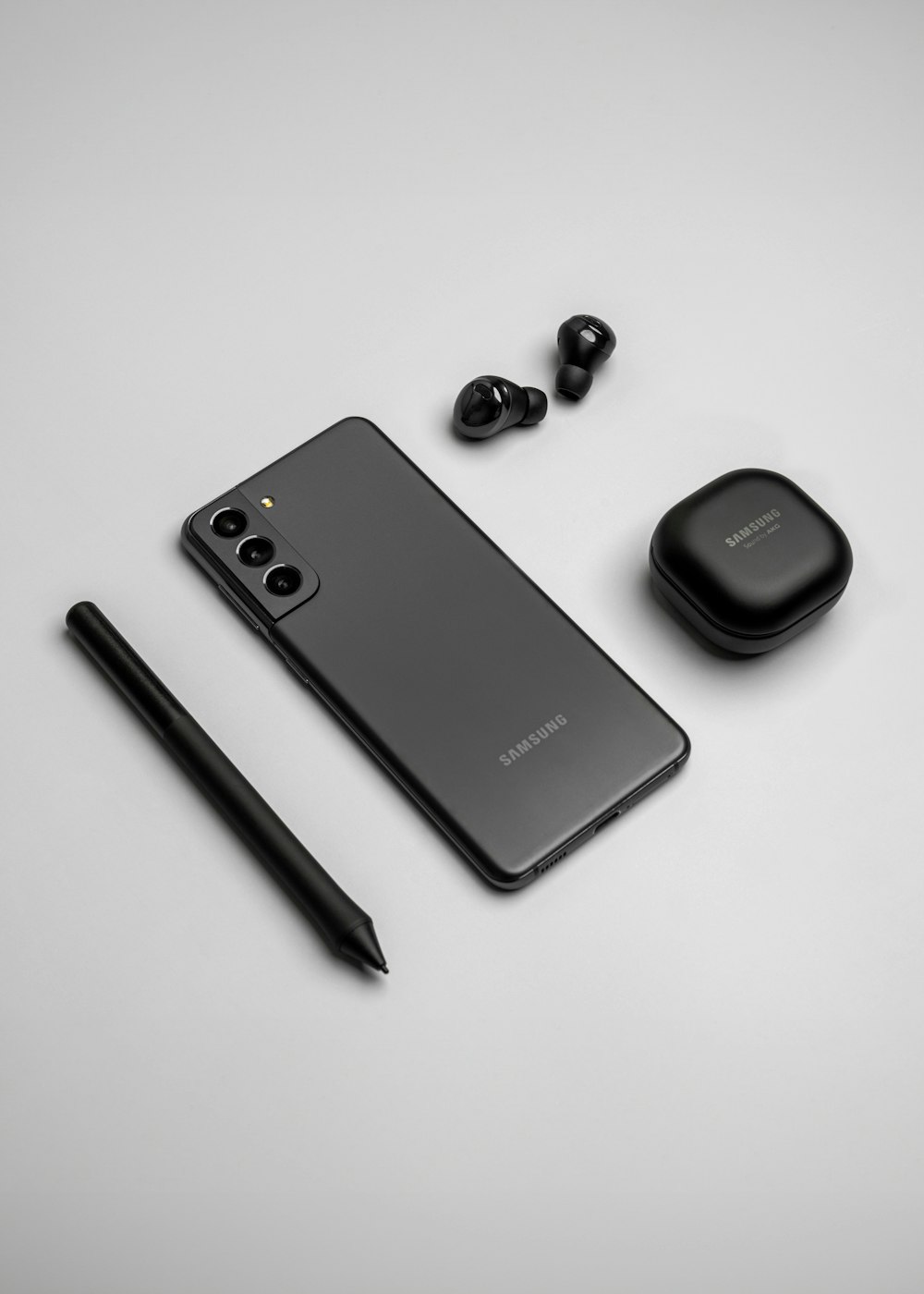 a cell phone, ear buds, and a pen on a table