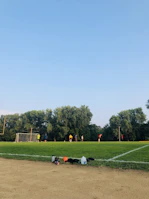 Kids and adults engaged in a friendly soccer match on the green field surrounded by trees.