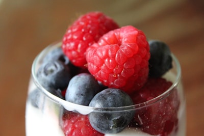 Vibrant mix of fresh blueberries and raspberries spilling from a rustic wooden crate.