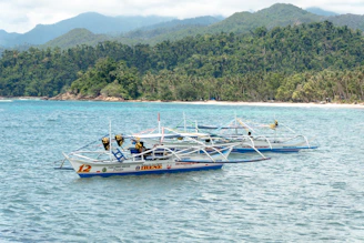A vibrant outrigger boat gliding over crystal-clear waters near lush green islands.