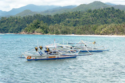 A vibrant outrigger boat gliding over crystal-clear waters near lush green islands.