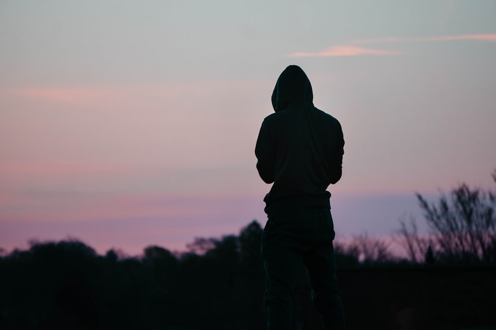 eine Silhouette einer Person in einem Kapuzenpullover, die in den Himmel schaut