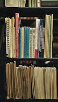 a bookshelf filled with lots of books and papers