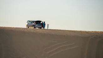 A mechanic assisting a stranded car on a Dubai roadside under a clear sky.
