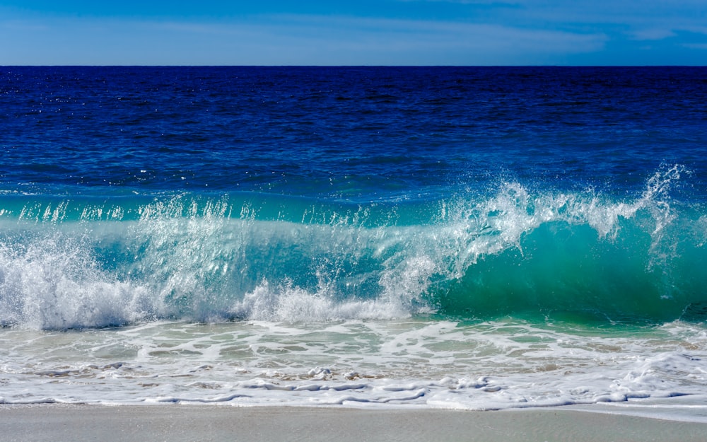 a wave crashes into the shore of a beach