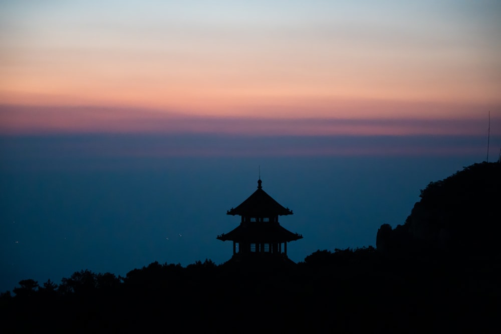 a silhouette of a pagoda on top of a hill