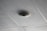 A ceiling with acoustic tiles arranged in a grid pattern and a round speaker or smoke detector mounted in the center of one tile.