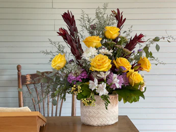 A bright and colorful flower arrangement displayed on a rustic wooden table.