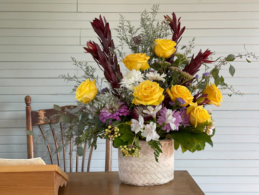 A bright and colorful flower arrangement displayed on a rustic wooden table.