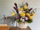 A vibrant flower board arrangement with yellow and white flowers on a wooden stand