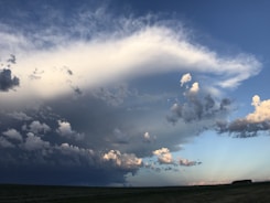 Landscape image with a dramatic blue sky filled with volumetric clouds.