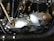 A close-up of a motorcycle engine part on a workbench, surrounded by tools and spare parts.