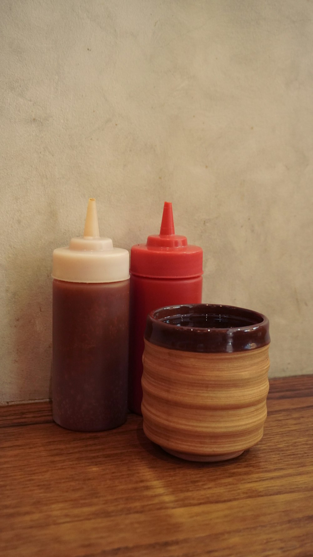 a wooden table topped with a bottle and a container