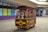 A candy cart filled with various jars of colorful candies, each with a dispenser. It is set in a shopping mall corridor with tiled floors and a partially visible storefront in the background.