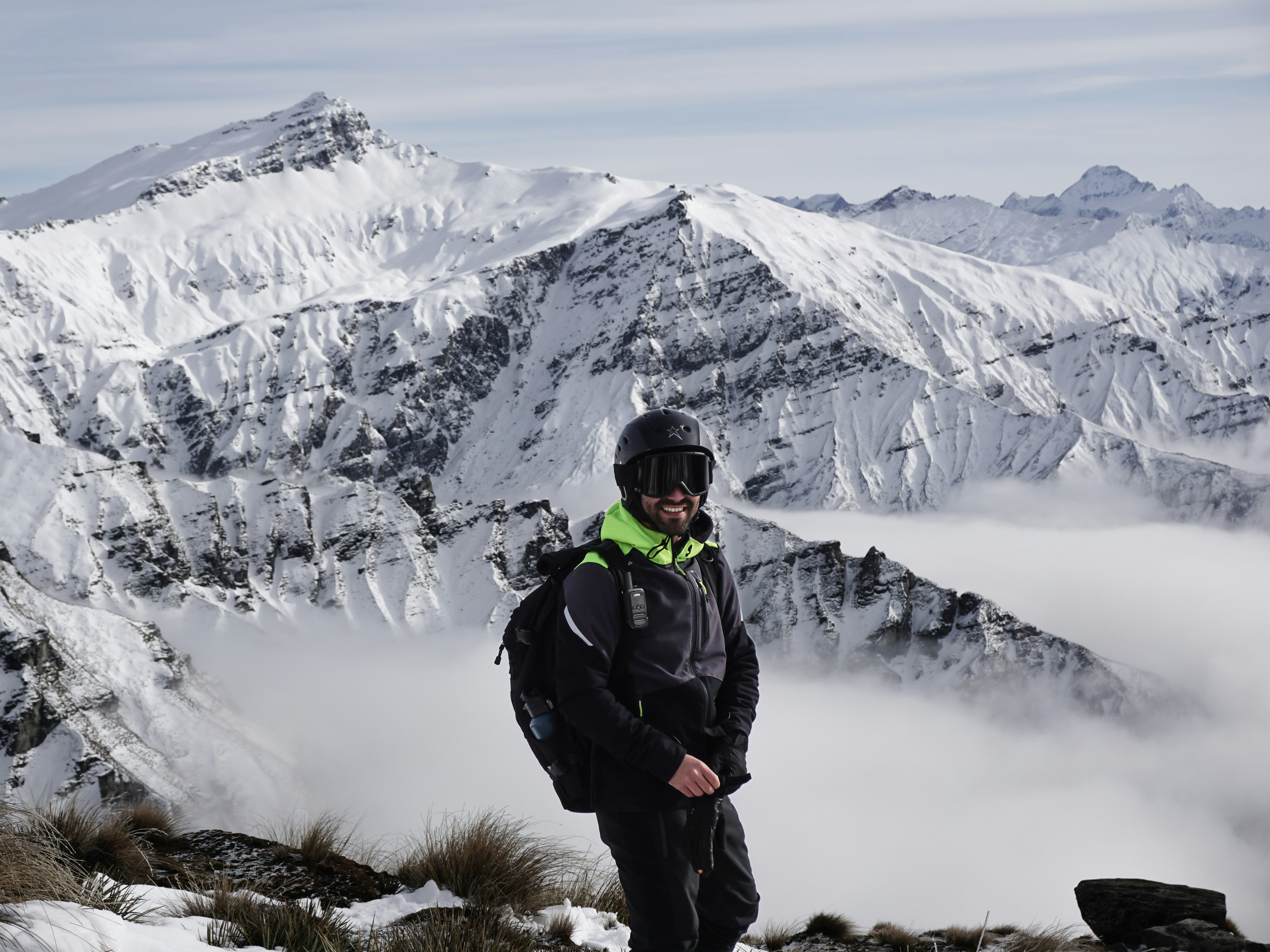 Portrait of a man in outdoor travel gear smiling against a mountain backdrop