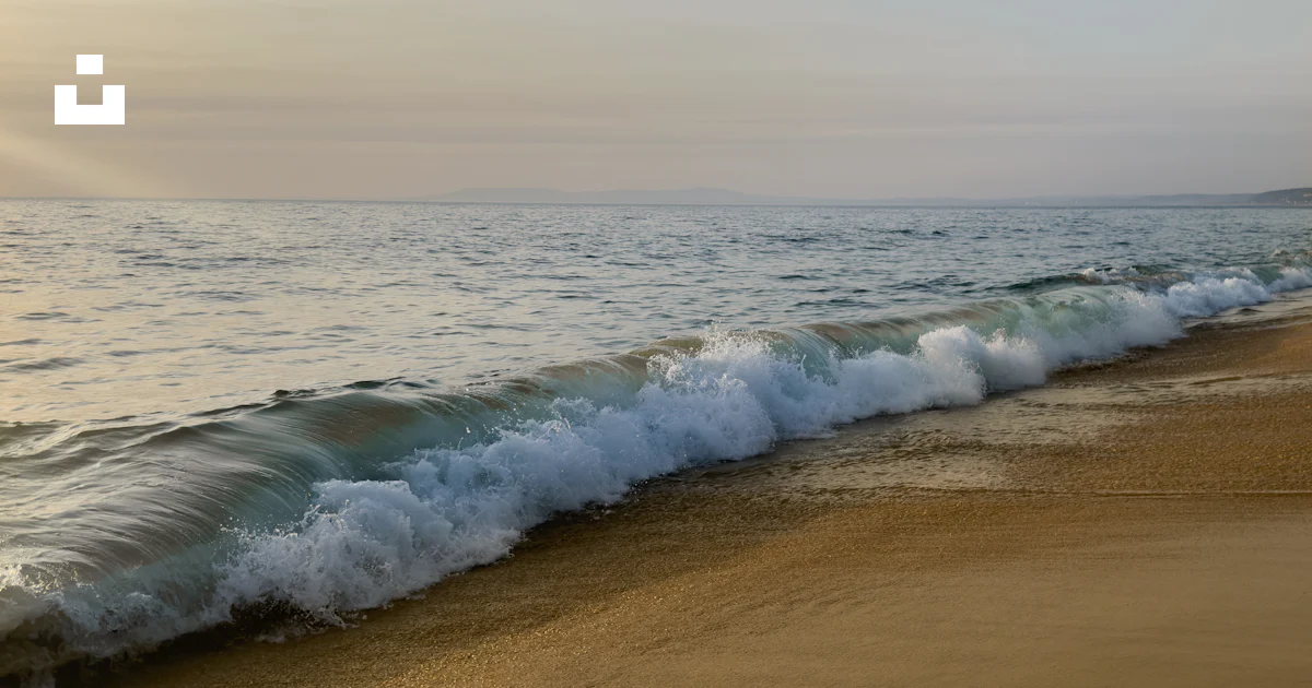Une plage de sable avec des vagues qui arrivent sur le rivage photo ...