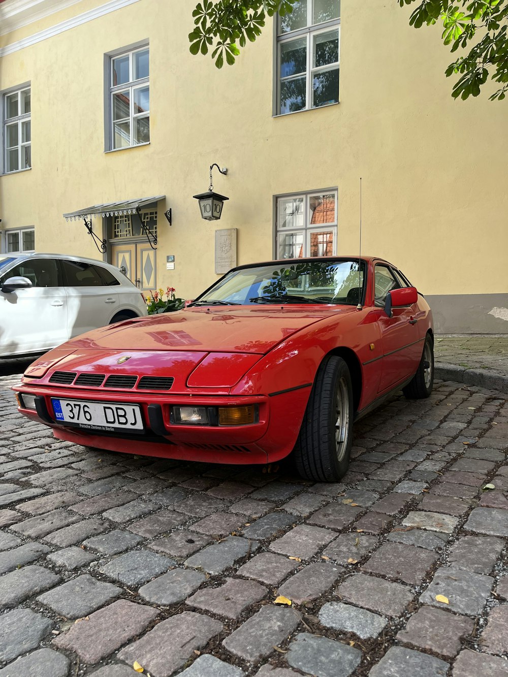 a red sports car parked in front of a yellow building