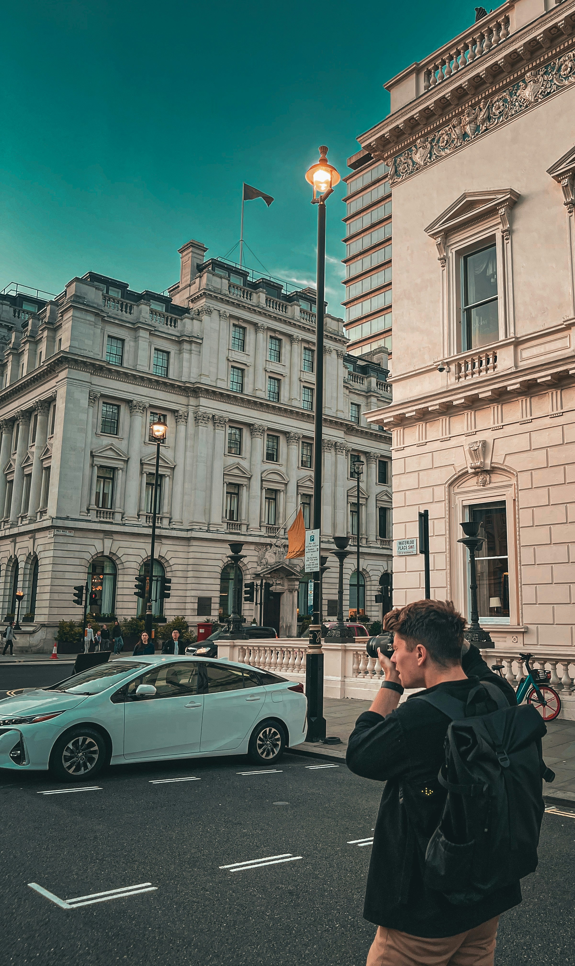 a man standing on the side of a road talking on a cell phone