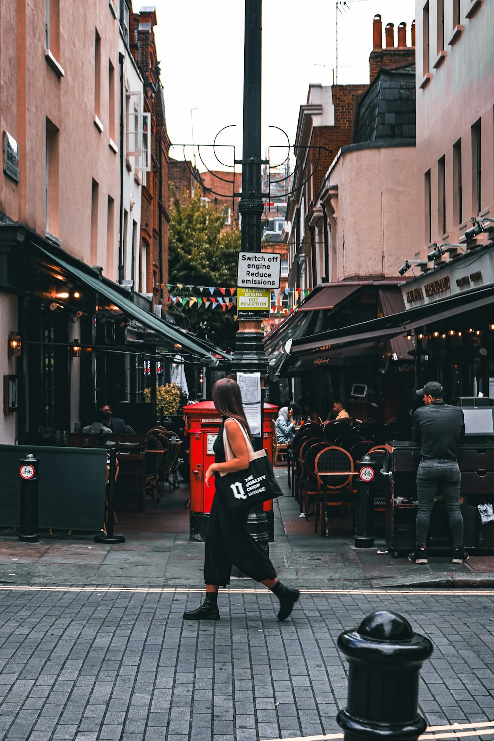 a woman walking down a street next to tall buildings