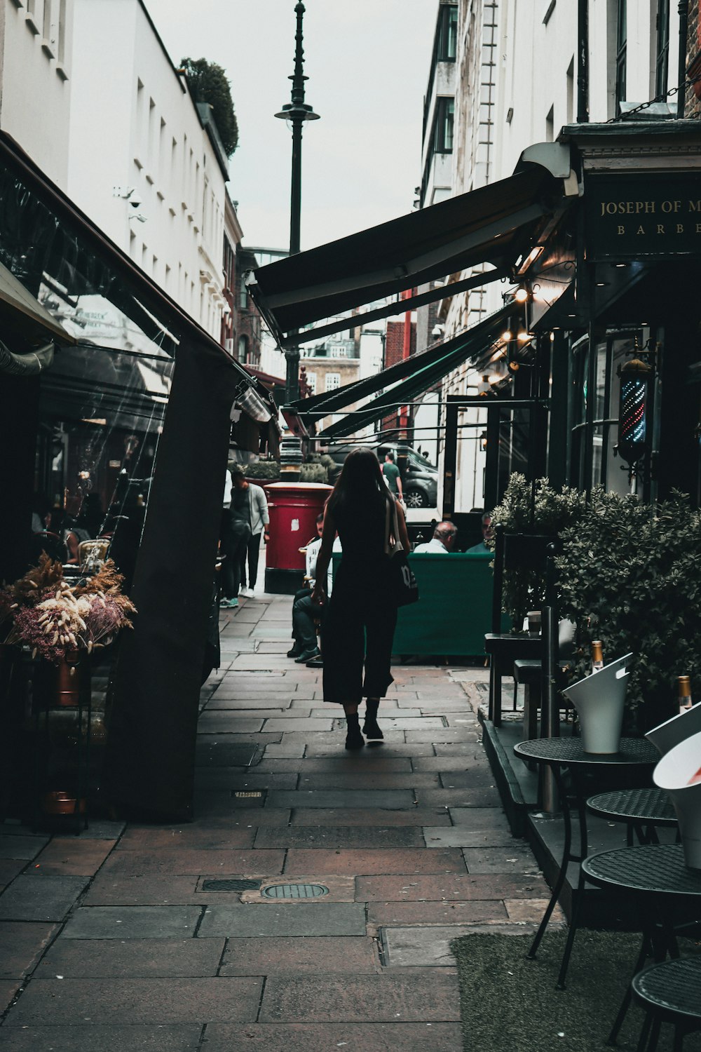 a woman walking down a street next to a tall building