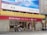 A bank building with signage for CMB Wing Lung Bank, featuring a large red and yellow sign with Chinese and English text. Several people are walking on the sidewalk in front of the building, and there are decorative stone lions by the entrance. Above the bank is a large blue and white advertisement billboard with cityscape graphics.