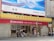 A bank building with signage for CMB Wing Lung Bank, featuring a large red and yellow sign with Chinese and English text. Several people are walking on the sidewalk in front of the building, and there are decorative stone lions by the entrance. Above the bank is a large blue and white advertisement billboard with cityscape graphics.