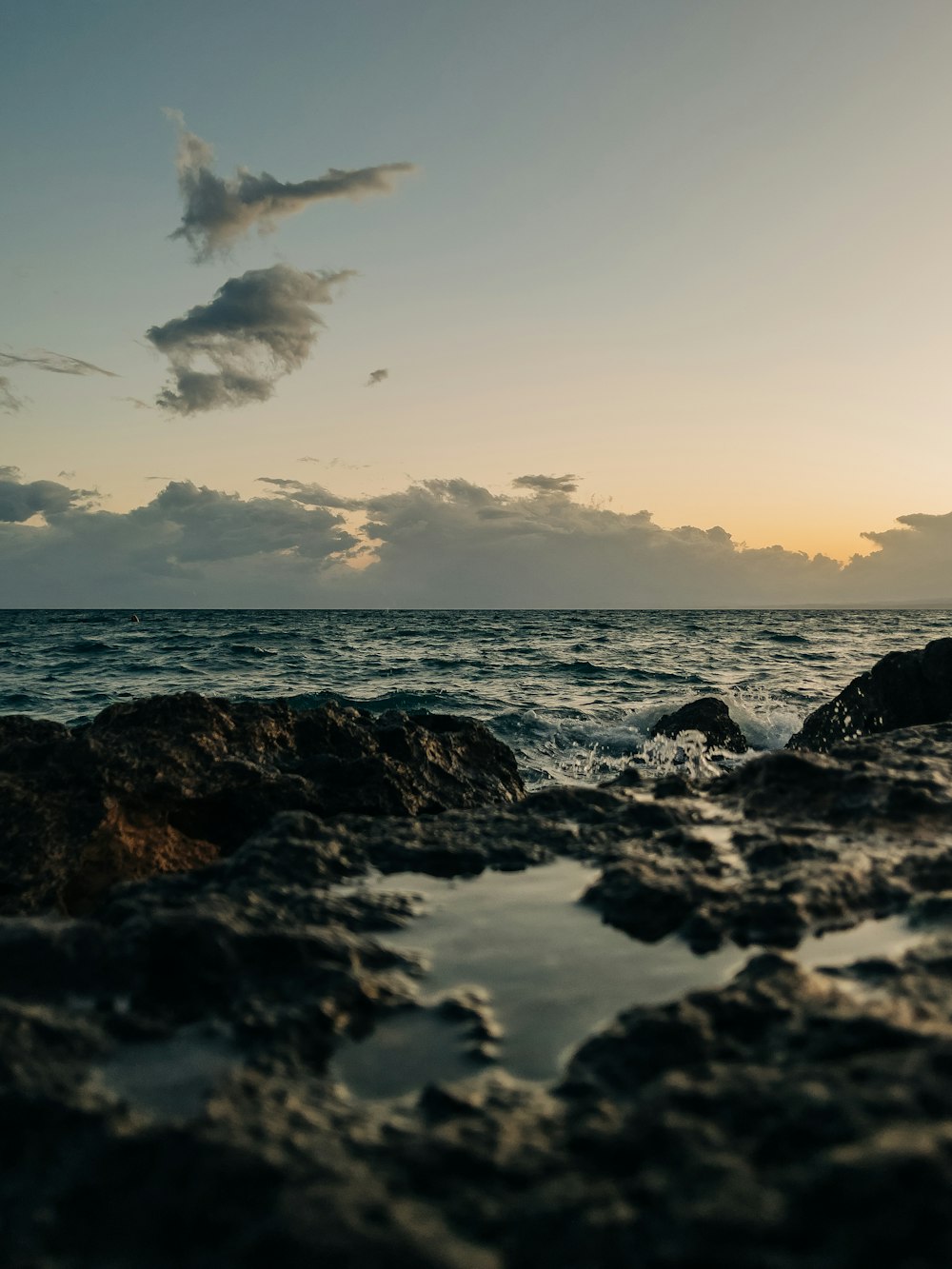 the sun is setting over the ocean and rocks